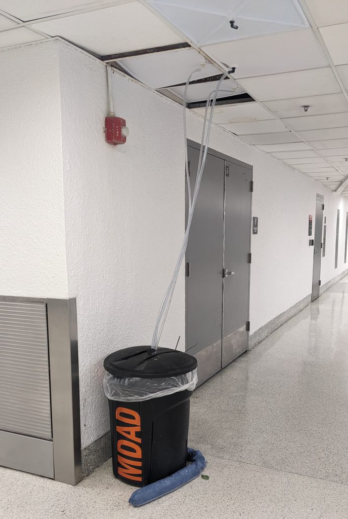 Garbage collectors collecting water from the ceiling panels at the Miami-Dade Airport.